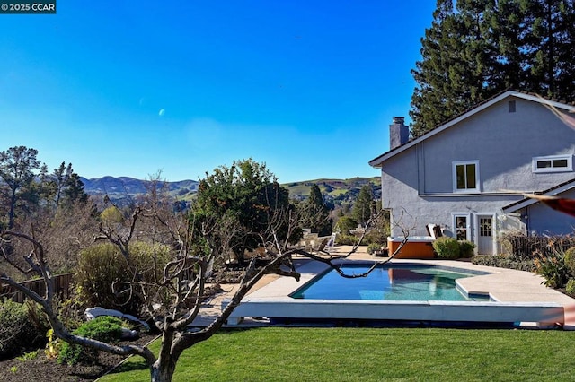 view of swimming pool featuring a jacuzzi, a lawn, and a mountain view