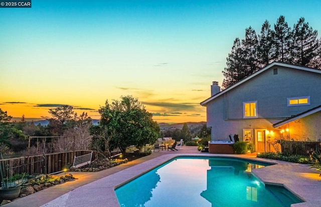 pool at dusk featuring a patio