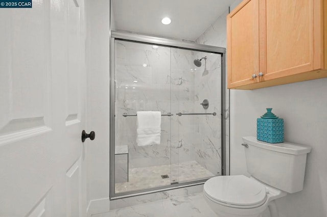 bathroom with a shower with shower door and toilet