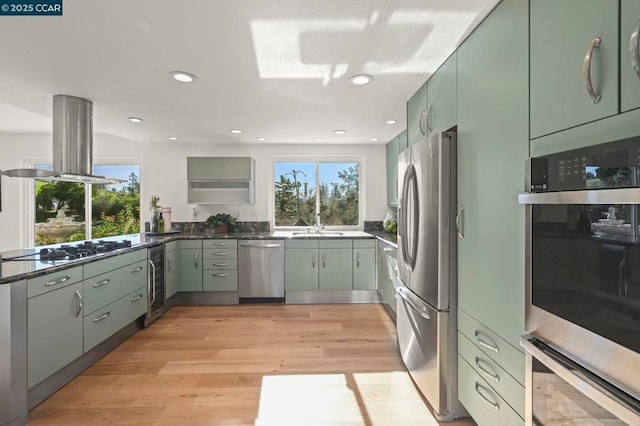 kitchen featuring stainless steel appliances, wine cooler, light hardwood / wood-style floors, island exhaust hood, and dark stone counters