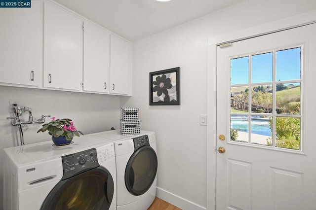 laundry room with cabinets, washing machine and clothes dryer, and light wood-type flooring