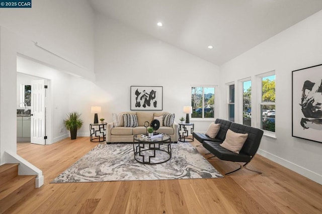 living room featuring sink, hardwood / wood-style flooring, and high vaulted ceiling