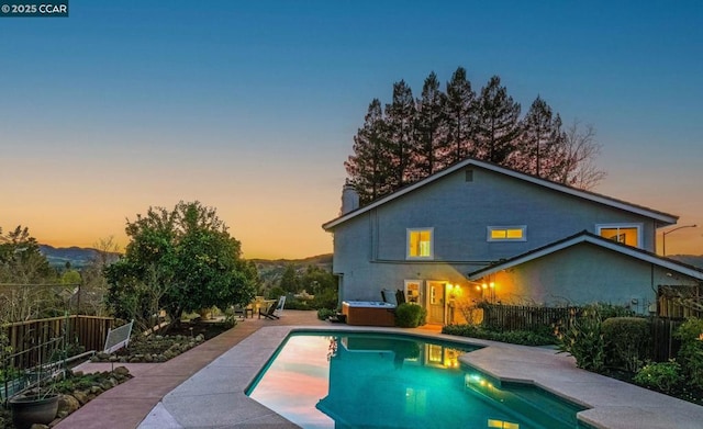 pool at dusk with a patio area and a jacuzzi