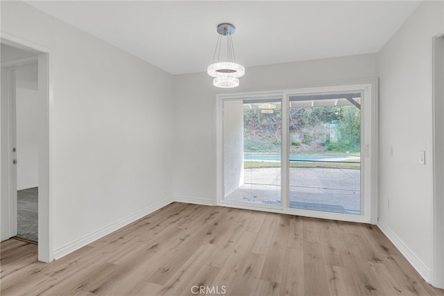 unfurnished dining area with light wood-type flooring and an inviting chandelier