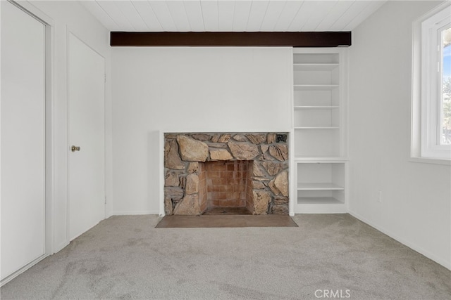 interior details with beam ceiling, built in shelves, a fireplace, and carpet flooring