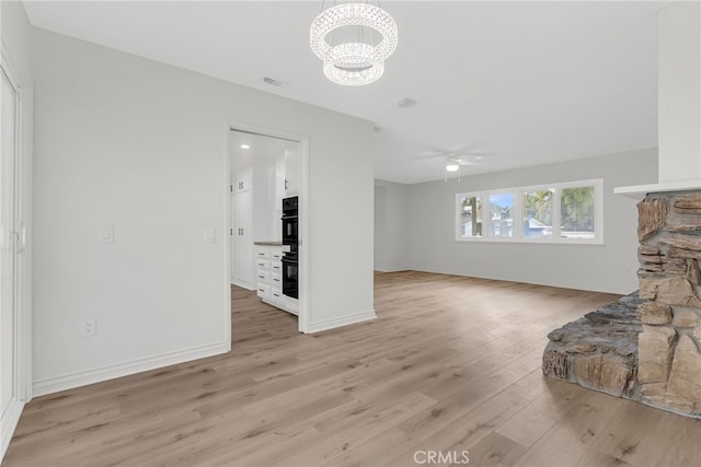 living room with ceiling fan with notable chandelier and light wood-type flooring