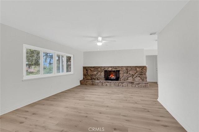 unfurnished living room featuring ceiling fan, a fireplace, and light hardwood / wood-style flooring