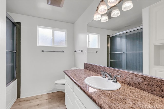 full bathroom with hardwood / wood-style flooring, vanity, combined bath / shower with glass door, and toilet