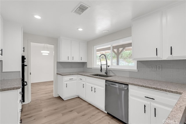 kitchen with sink, white cabinets, stainless steel dishwasher, light stone countertops, and light hardwood / wood-style flooring