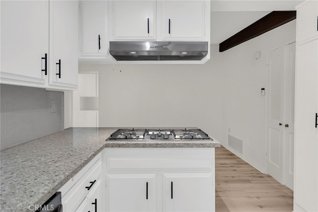 kitchen with beam ceiling, light stone countertops, stainless steel gas cooktop, and white cabinets