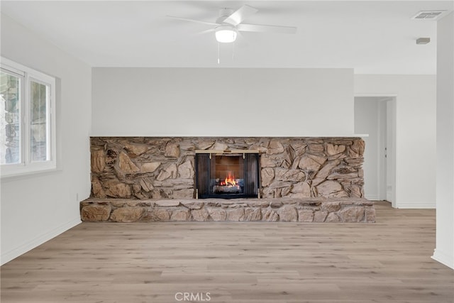 details featuring hardwood / wood-style floors, a stone fireplace, and ceiling fan