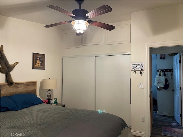 bedroom with dark hardwood / wood-style floors, a closet, and ceiling fan