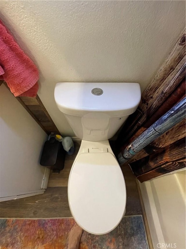 bathroom with wood-type flooring, toilet, and a textured ceiling