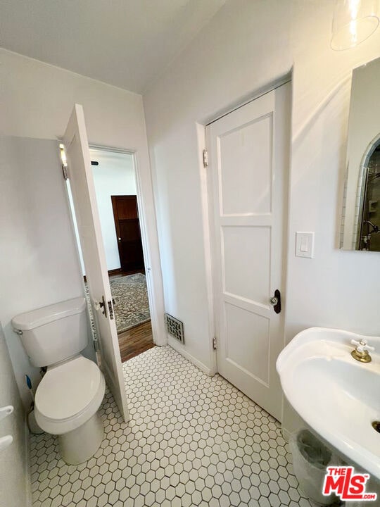 bathroom with sink, toilet, and tile patterned flooring