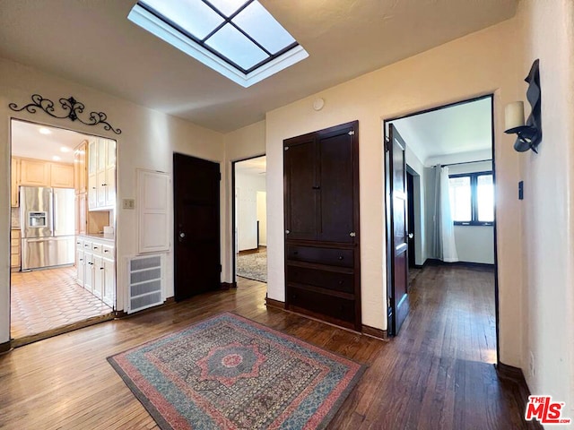 hall with a skylight and dark hardwood / wood-style floors