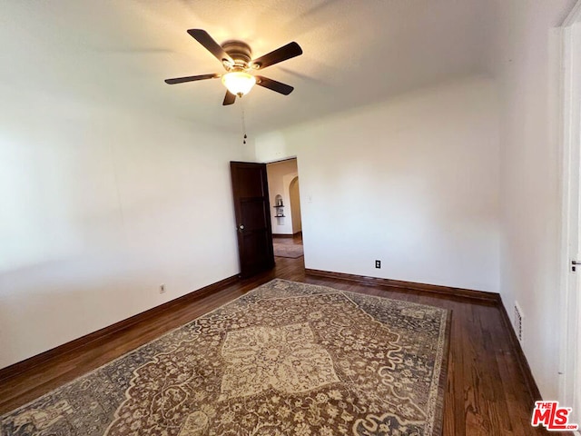 empty room with ceiling fan and dark hardwood / wood-style floors