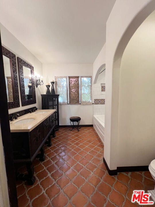 bathroom featuring tiled tub, toilet, and vanity