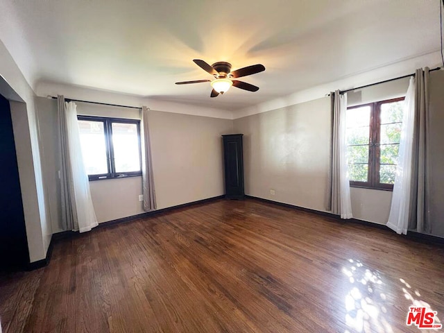 spare room featuring ceiling fan, a wealth of natural light, and dark hardwood / wood-style floors