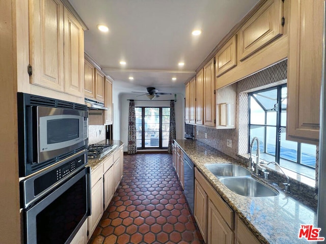 kitchen featuring light brown cabinets, appliances with stainless steel finishes, sink, backsplash, and light stone counters