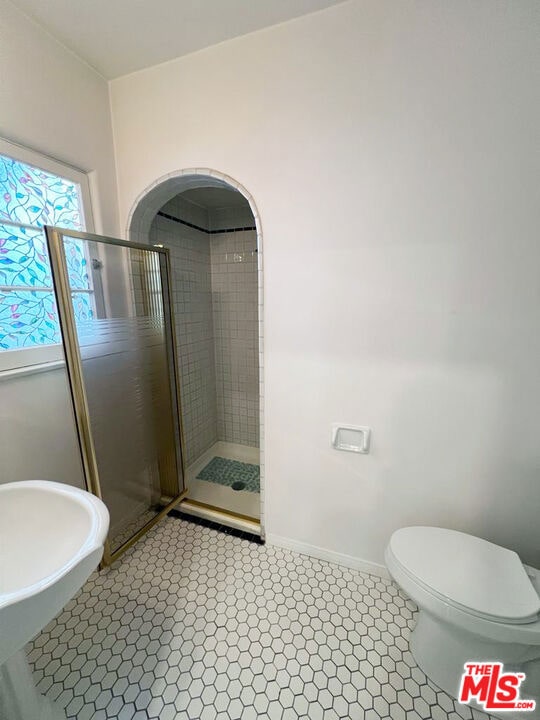 bathroom with toilet, an enclosed shower, and tile patterned floors