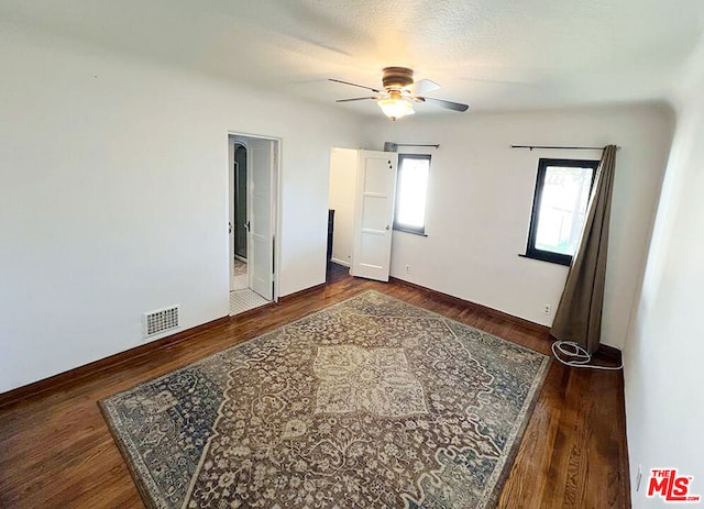 bedroom featuring ceiling fan, dark hardwood / wood-style floors, and a textured ceiling