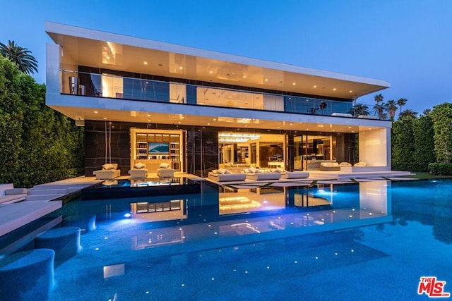 pool at dusk featuring outdoor lounge area and a patio area