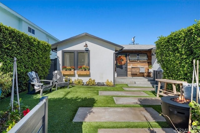 back of property with a lawn, an outdoor fire pit, and a patio