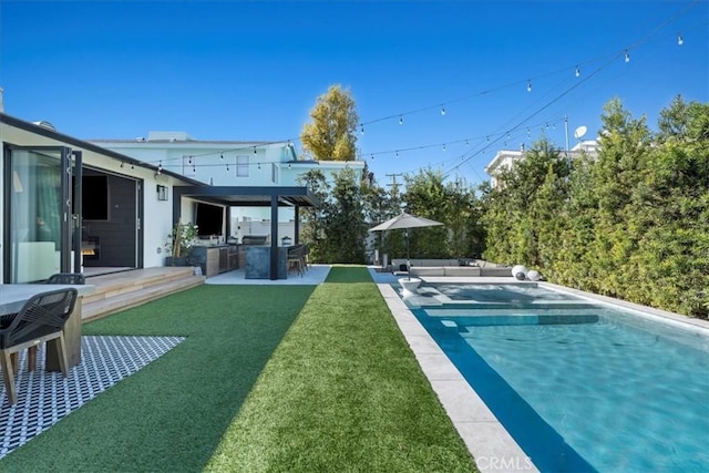 view of swimming pool featuring a bar, an outdoor kitchen, a lawn, and a patio