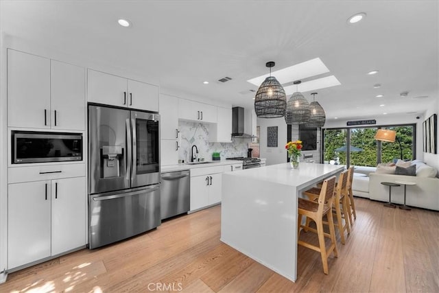 kitchen featuring tasteful backsplash, white cabinetry, decorative light fixtures, a breakfast bar, and stainless steel appliances