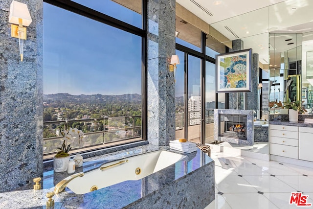 bathroom with exterior fireplace, a mountain view, tile patterned floors, floor to ceiling windows, and a bathing tub