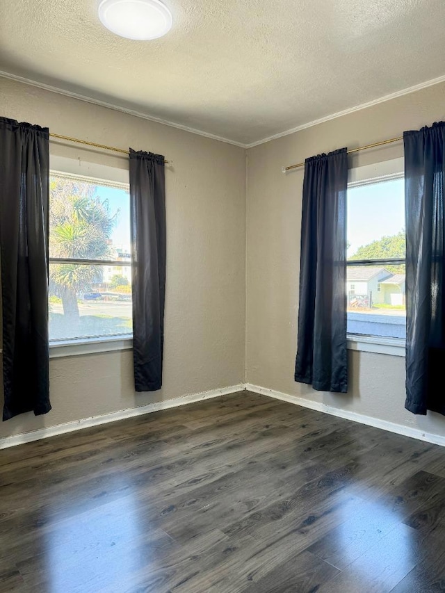 spare room featuring dark wood-type flooring, ornamental molding, and a textured ceiling