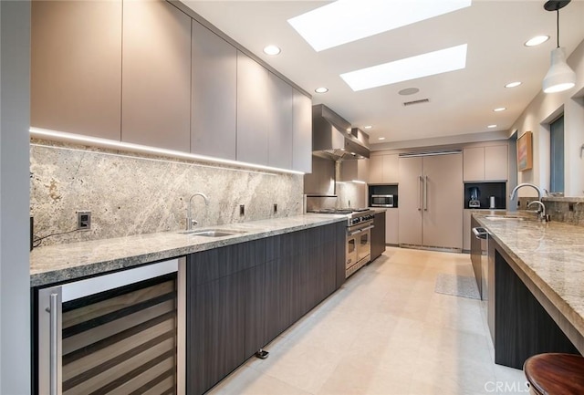 kitchen with wine cooler, sink, extractor fan, hanging light fixtures, and premium appliances