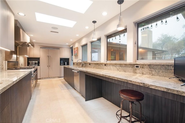 kitchen featuring pendant lighting, a breakfast bar area, a skylight, high end appliances, and island range hood