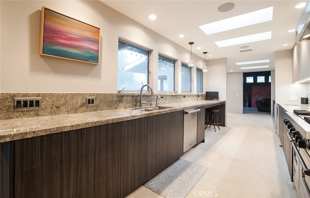 kitchen featuring pendant lighting, sink, dishwasher, a skylight, and dark brown cabinetry