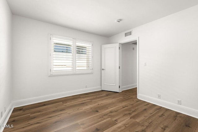 unfurnished room with dark wood-type flooring