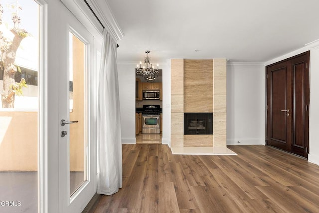 unfurnished living room with plenty of natural light, wood-type flooring, crown molding, and a fireplace