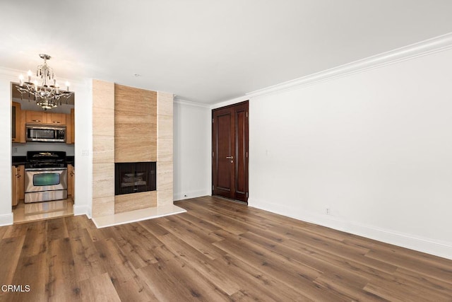 unfurnished living room with dark hardwood / wood-style floors, a tile fireplace, ornamental molding, and a chandelier