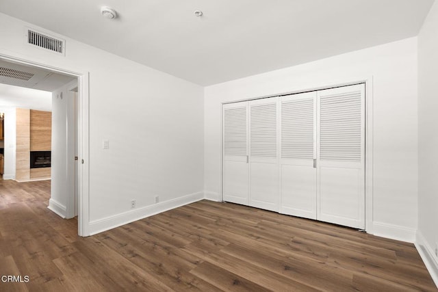 unfurnished bedroom featuring a fireplace, dark hardwood / wood-style floors, and a closet