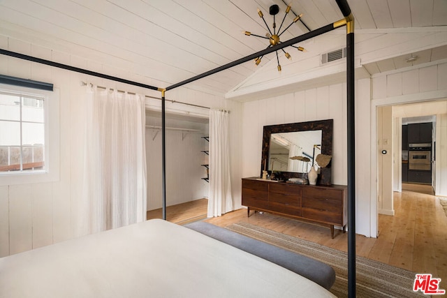 bedroom with vaulted ceiling, hardwood / wood-style floors, wooden ceiling, wood walls, and a closet