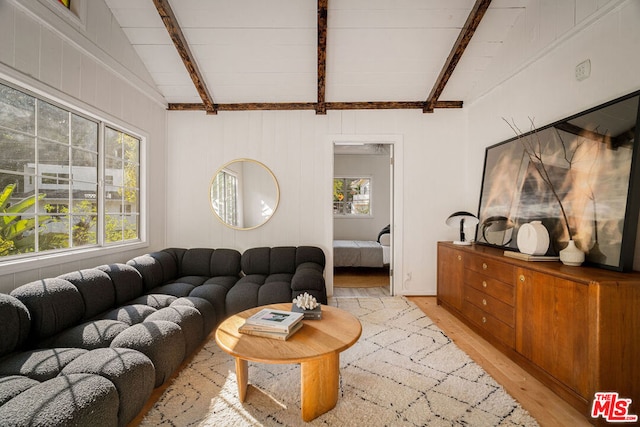 living room with light hardwood / wood-style flooring and vaulted ceiling with beams