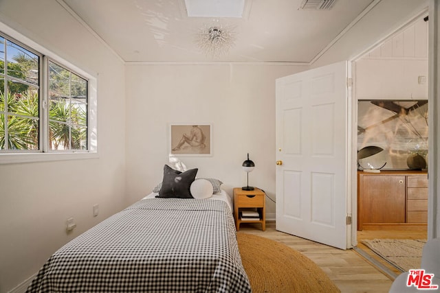 bedroom with ornamental molding and light hardwood / wood-style flooring