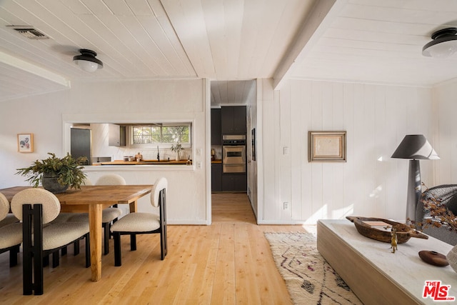 dining area with light wood-type flooring, beamed ceiling, wooden walls, and wooden ceiling