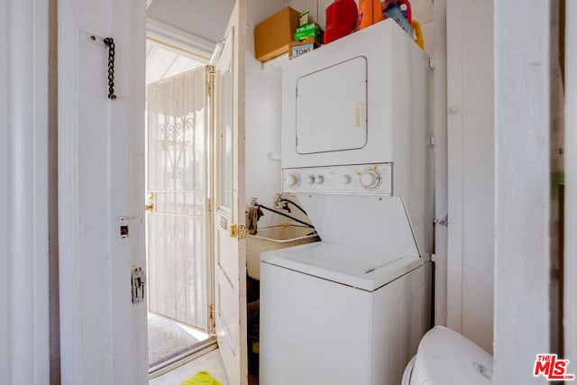 washroom with sink and stacked washer / drying machine