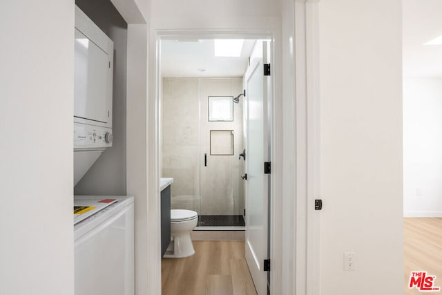 bathroom featuring an enclosed shower, stacked washer / drying machine, vanity, toilet, and hardwood / wood-style flooring