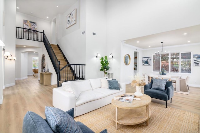 living room with light hardwood / wood-style flooring, a chandelier, crown molding, and plenty of natural light