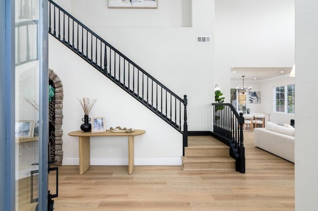 stairway with wood-type flooring, crown molding, and a chandelier