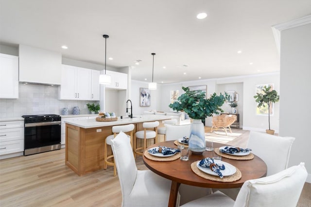 dining space featuring sink, crown molding, and light wood-type flooring