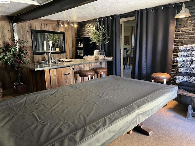 interior space featuring brick wall, decorative light fixtures, pool table, carpet flooring, and beam ceiling