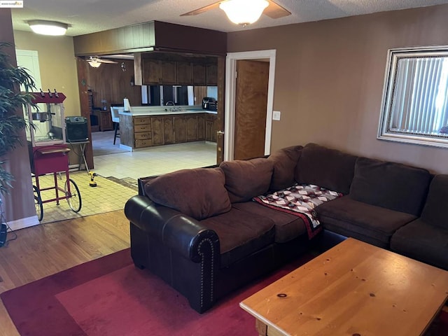 living room featuring sink, ceiling fan, and a textured ceiling