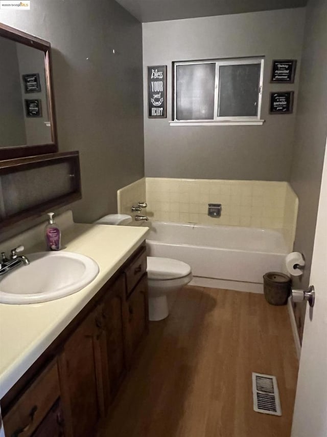 bathroom featuring hardwood / wood-style floors, toilet, vanity, and a bathing tub